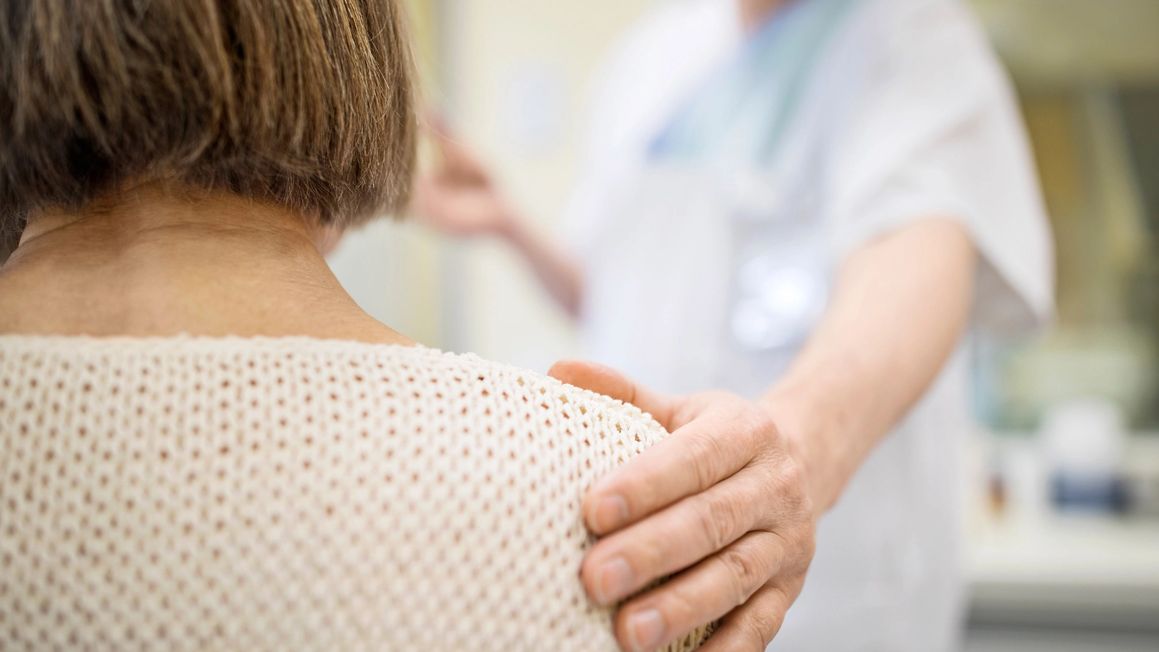 Eine Pflegerin fasst einer älteren Frau an die Schulter.