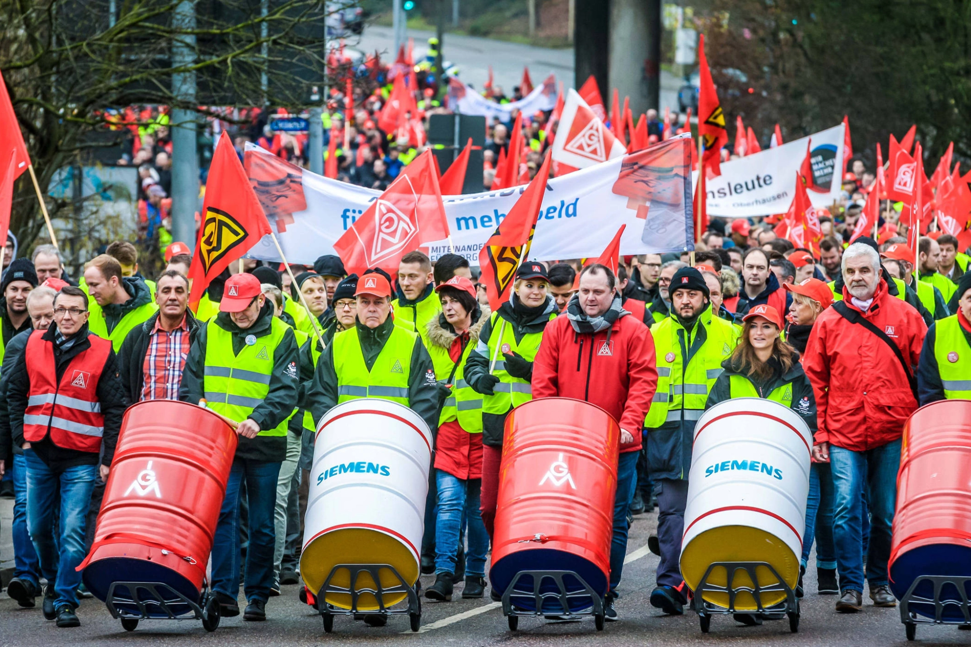 Streikende an der Spitze eines Demonstrationszuges, die auf Fässern trommeln.