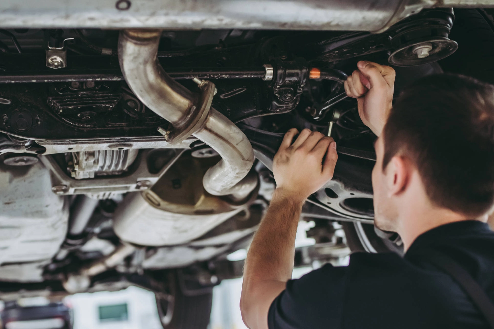 Zwei Männer stehen unter einer Hebebühne und arbeiten an einem Auto.