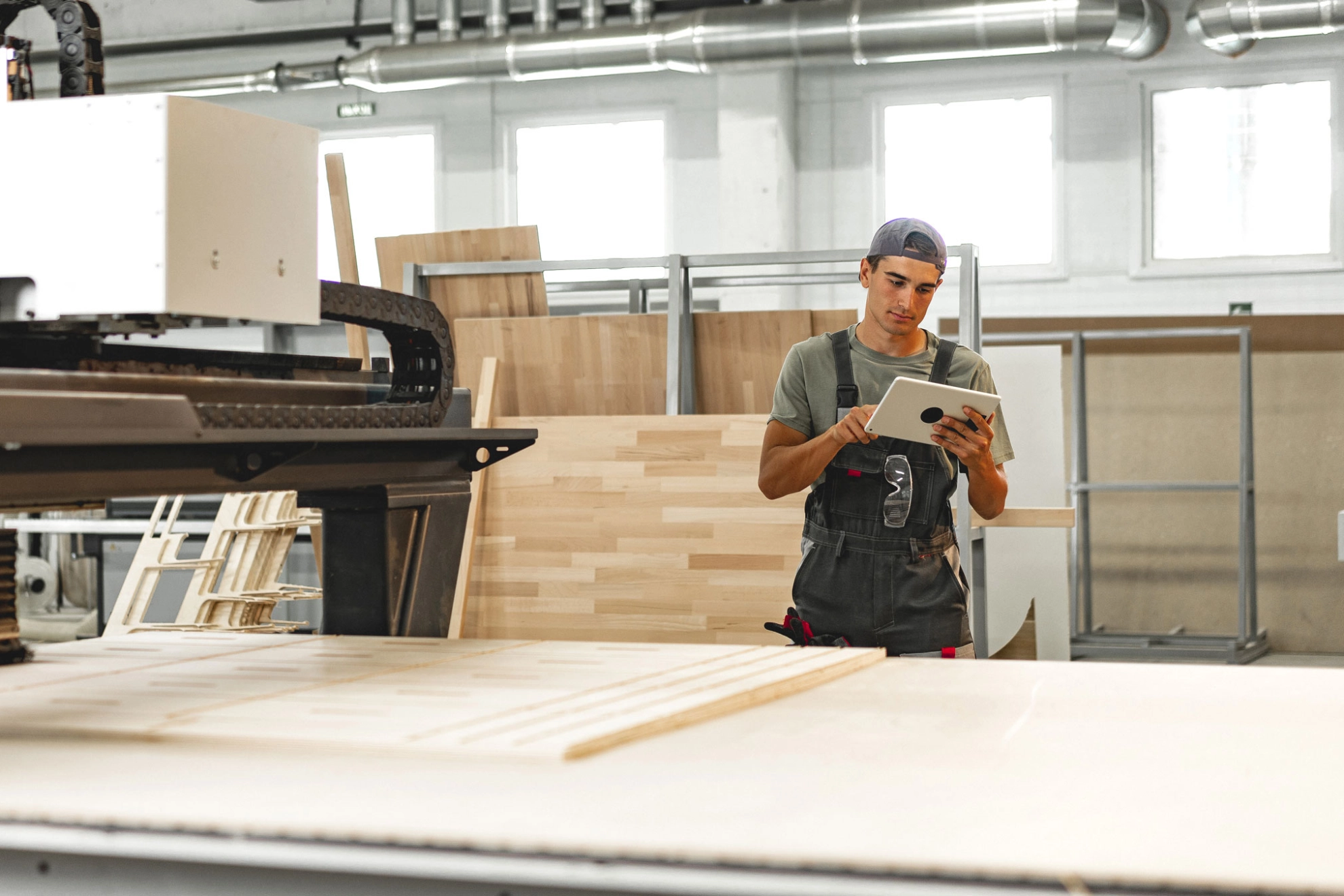 Beschäftigter bedient in einer Möbelfabrik eine Maschine zur Holzverarbeitung