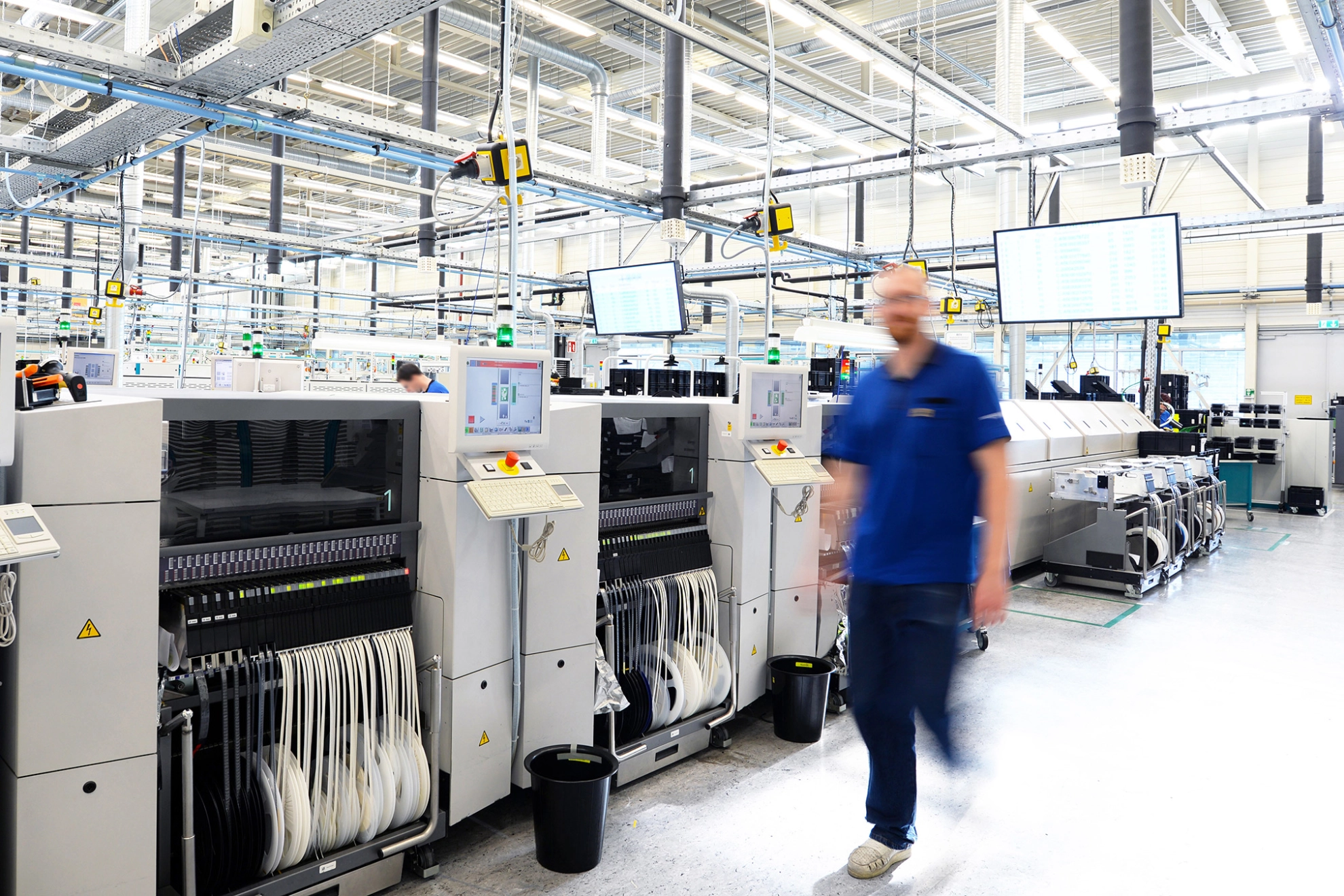 Ein Beschäftigter bedient Maschinen in einer Hightech-Fabrik über einen Monitor