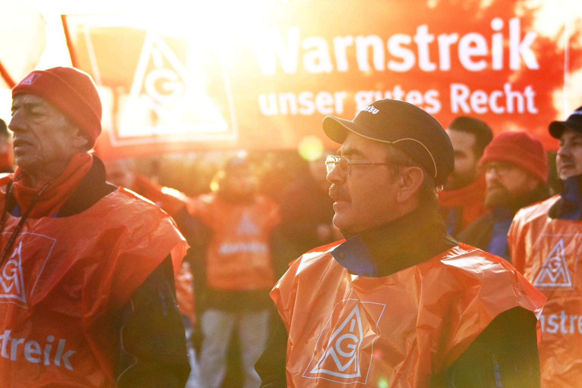 Eine Gruppe streikende Männer wird von der Sonne angestrahlt.